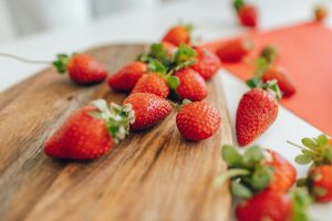 Close-up of fresh strawberries on a wooden chopping board with a blurred background.
